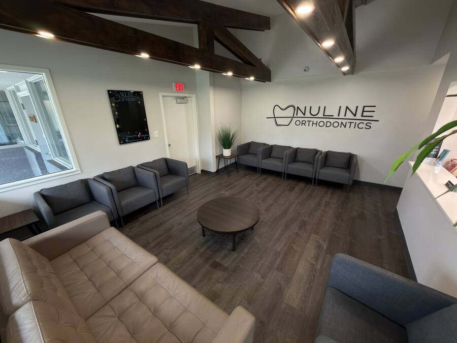 Waiting room with vaulted wood beams and the NuLine Orthodontics wall sign at the Beloit office