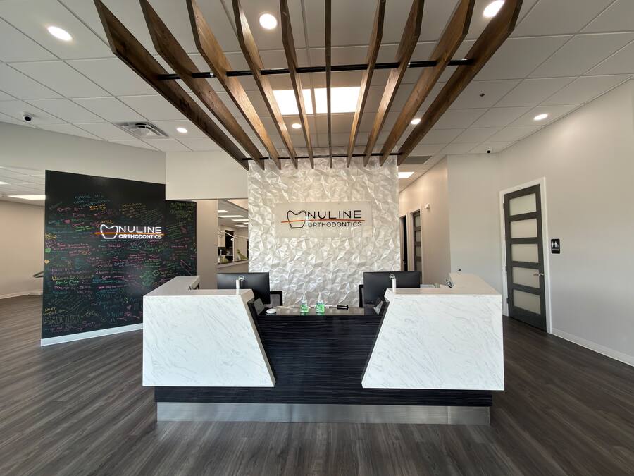 Reception desk beneath the NuLine Orthodontics sign at the Greenfield office